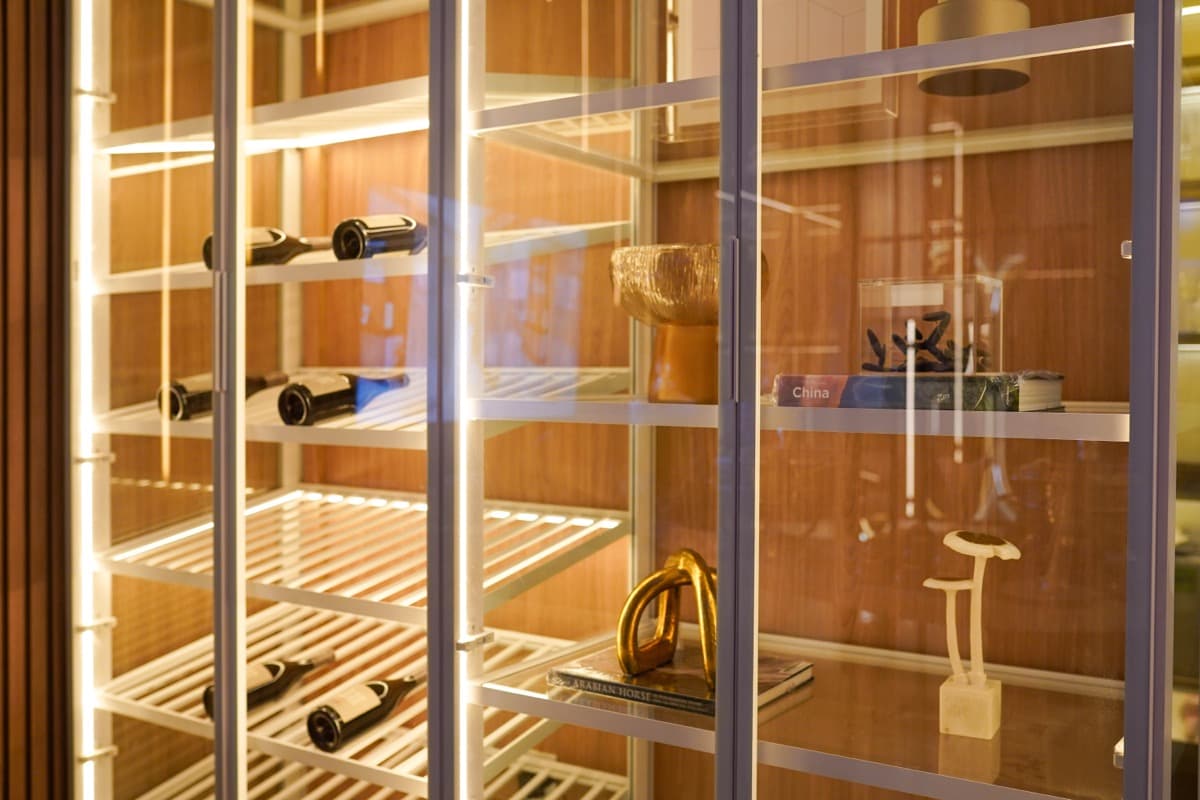 Estante iluminada com vinhos e objetos de decoração